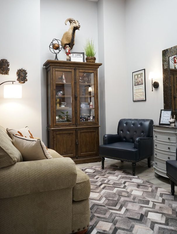 The waiting area — a couch, a leather chair and a wooden display cabinet