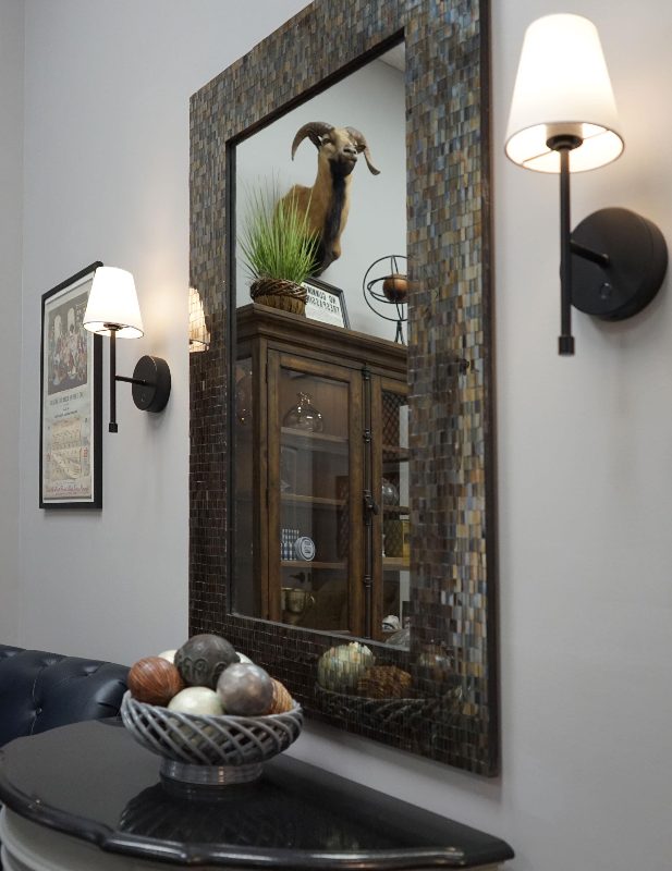 A tiled mirror and wall sconces above the waiting room table