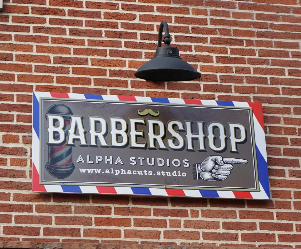 The Alpha Studios Barbershop sign on the brick wall outside the shop